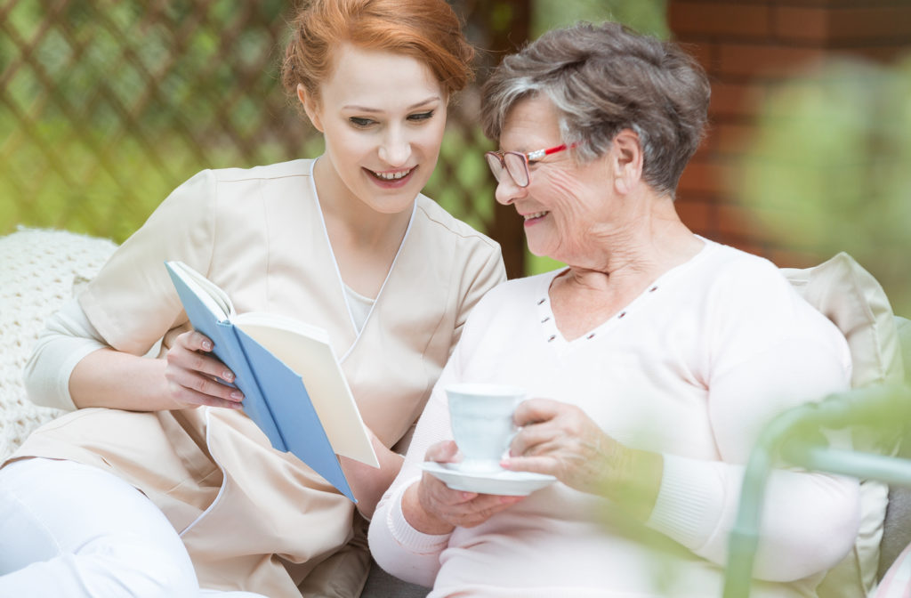Nurse helping senior women with memory care while looking at pictures while drinking from cup
