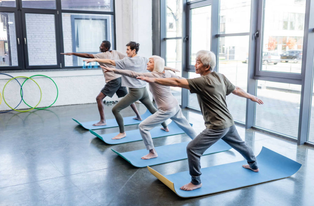 A group of seniors doing a balance exercise at the gym.