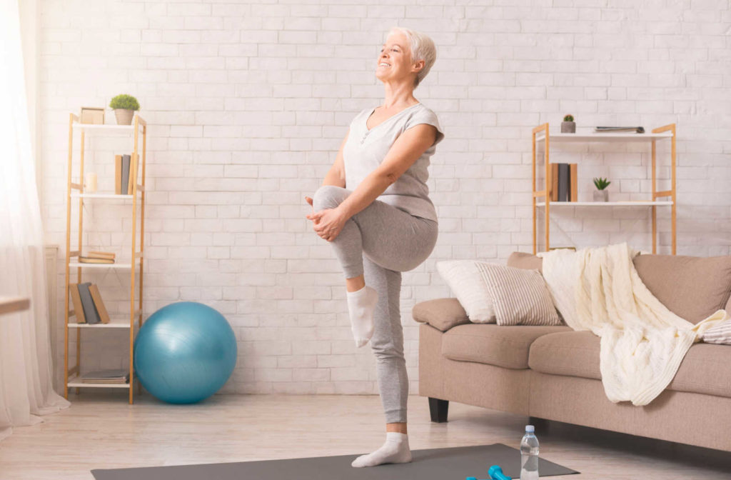 A female senior doing a balance exercise in her home.