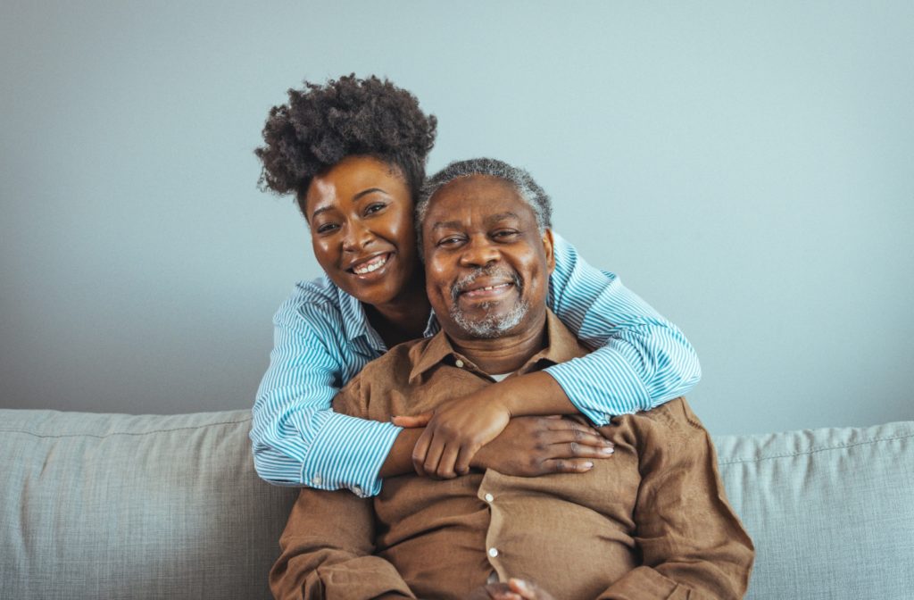 Loving senior man is embraced by his adult daughter.