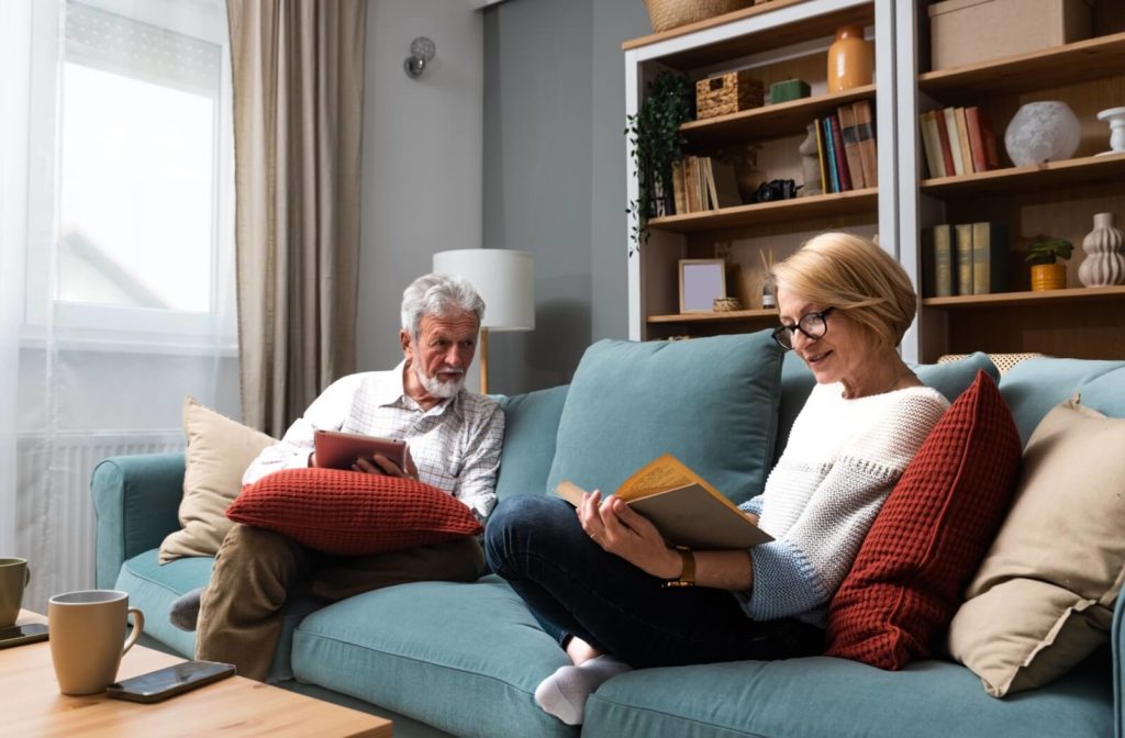 A senior couple sits on a couch creating a packing list together.