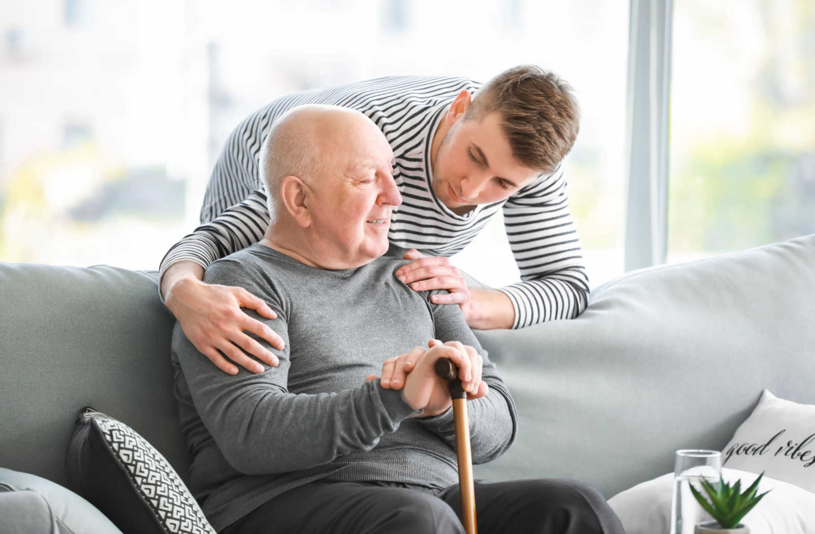 Young man checks in on his father who is sitting on the couch.