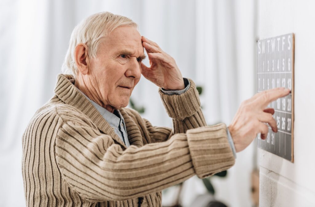 An older adult looks at a calendar and struggles to remember appointments.