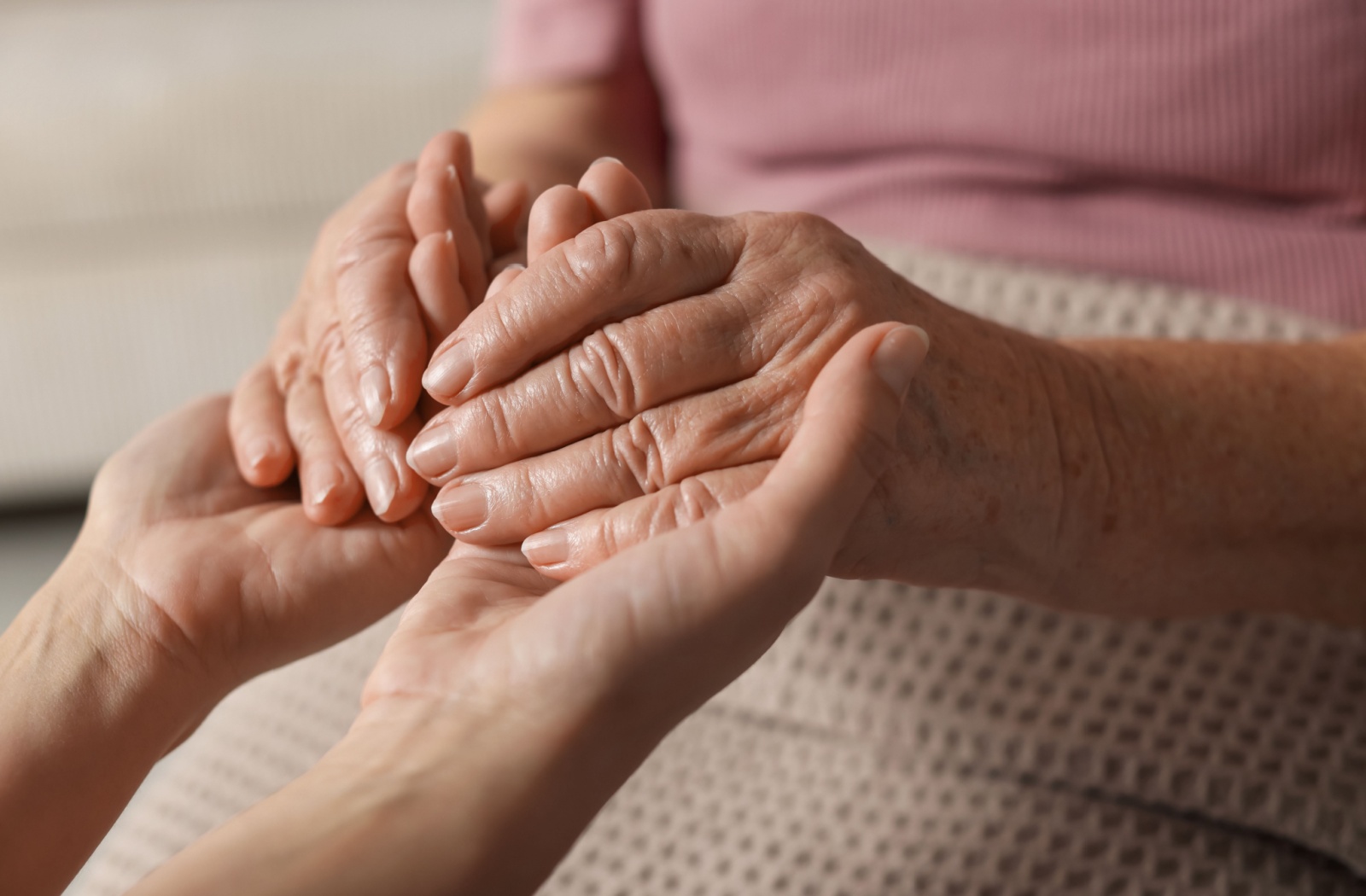 A senior holding hands with a caregiver in a memory care facility.