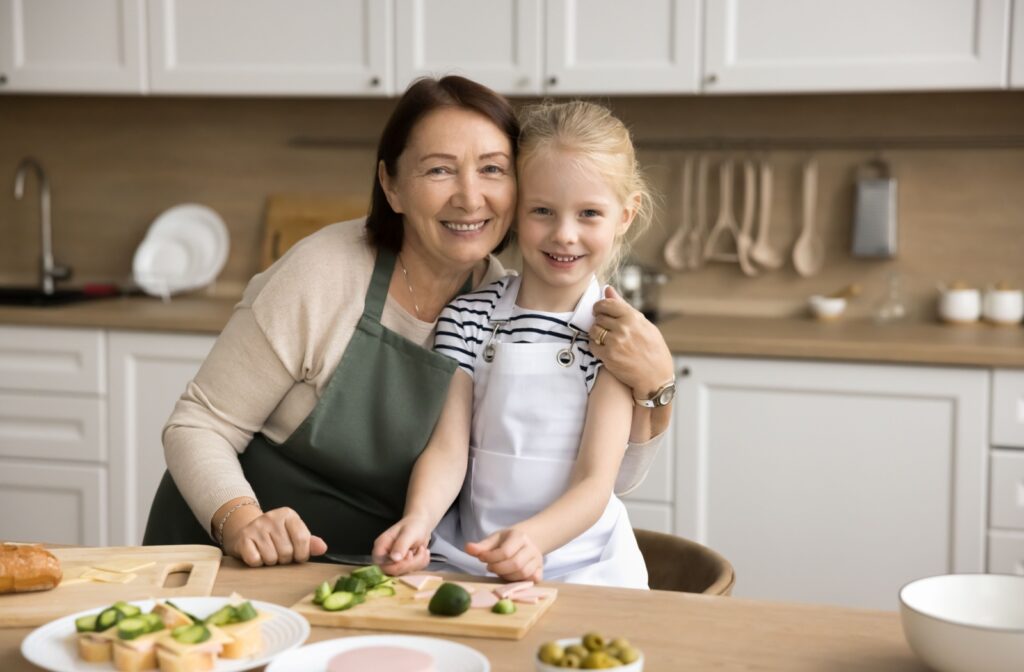 An older adult hugging their grandchild while slicing vegetables for a healthy breakfast.