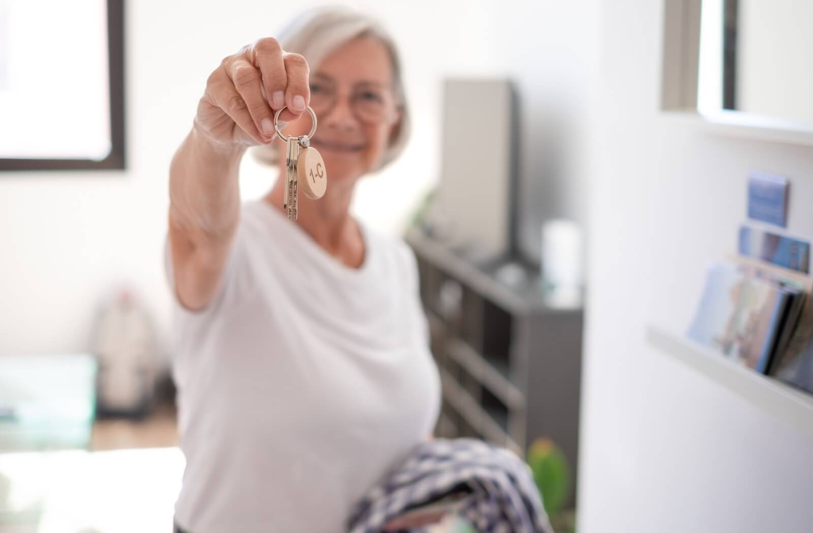 Blurred smiling senior holding home keys.
