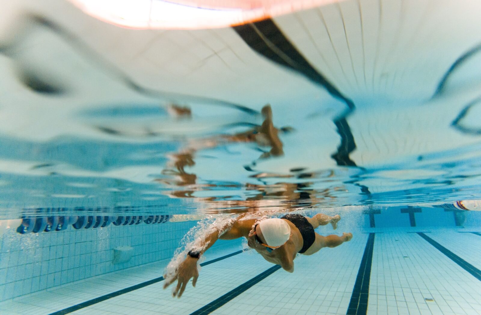 An active senior swims laps in a public pool as their choice of low-impact exercise to stay healthy and fit